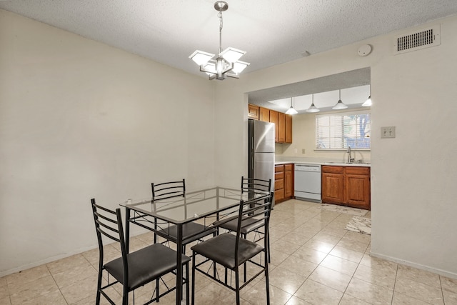 tiled dining space featuring a textured ceiling, sink, and a chandelier