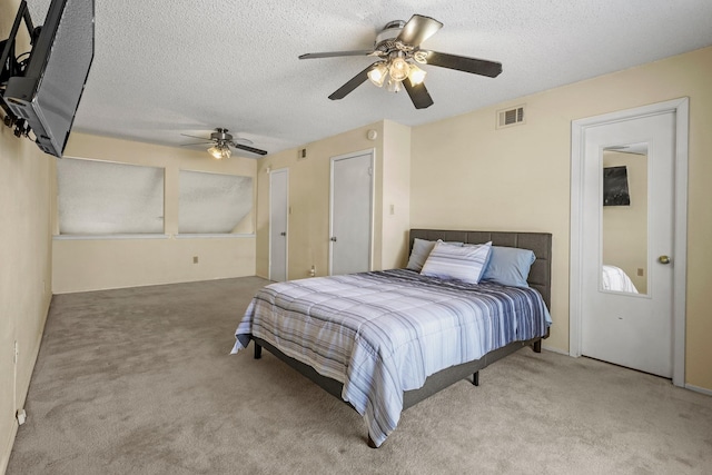 carpeted bedroom featuring ceiling fan and a textured ceiling