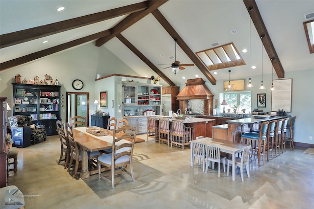 dining space with ceiling fan, beam ceiling, high vaulted ceiling, and a skylight