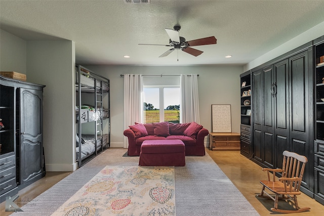 living room with ceiling fan and a textured ceiling