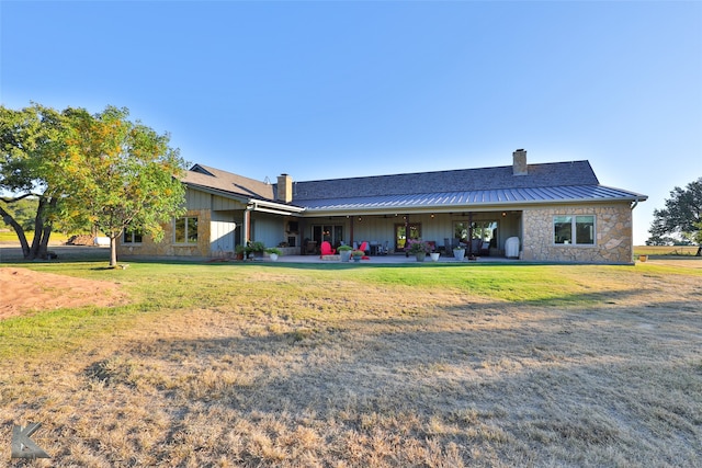 rear view of house with solar panels, a patio, and a lawn