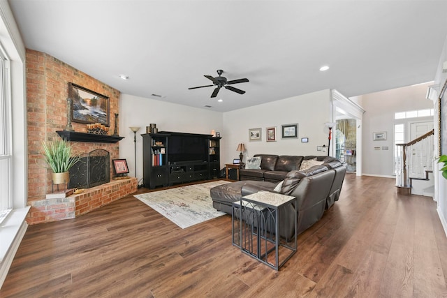 living room featuring ceiling fan, a fireplace, and dark hardwood / wood-style floors