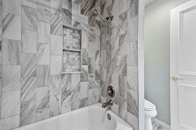 bathroom featuring toilet and tiled shower / bath