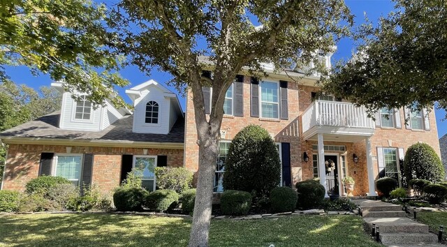 view of front of home featuring a balcony and a front lawn