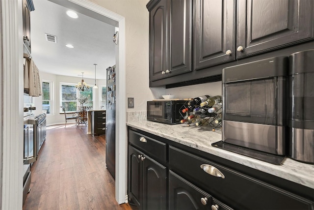 kitchen featuring dark hardwood / wood-style floors, light stone counters, dark brown cabinets, and a chandelier