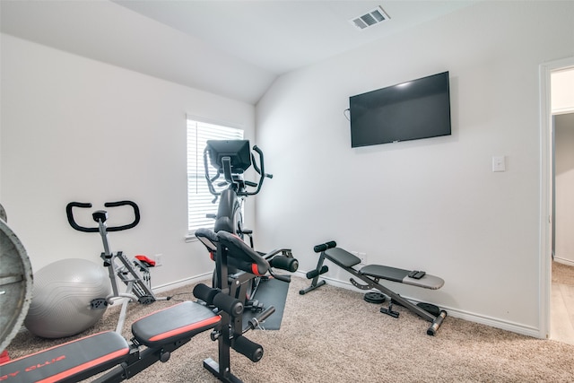 exercise room featuring vaulted ceiling and carpet flooring