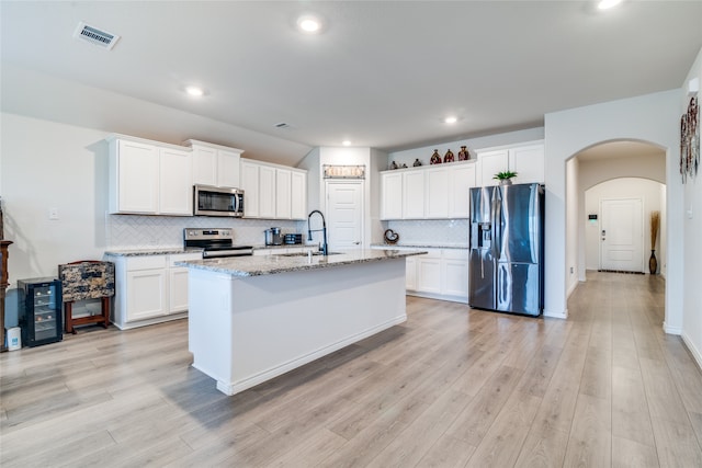 kitchen featuring light wood-type flooring, appliances with stainless steel finishes, sink, and tasteful backsplash