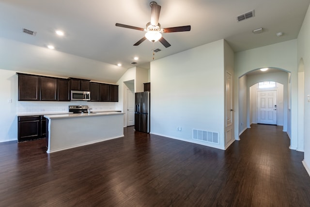 kitchen featuring appliances with stainless steel finishes, dark brown cabinetry, lofted ceiling, dark wood-type flooring, and a kitchen island with sink