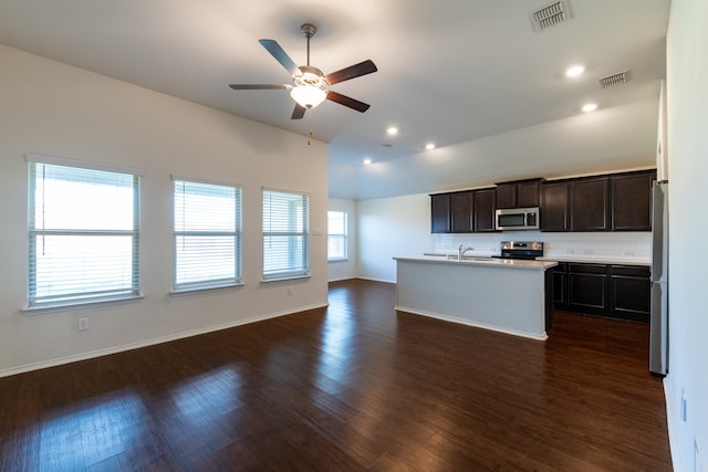 kitchen featuring stainless steel appliances, a kitchen island with sink, a wealth of natural light, and dark hardwood / wood-style flooring