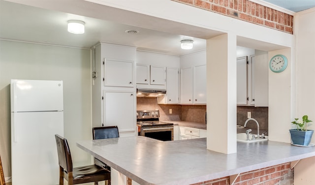 kitchen with sink, stainless steel electric range, white cabinets, a breakfast bar, and white refrigerator