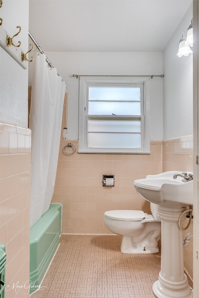 bathroom with toilet, tile walls, and shower / bathtub combination with curtain