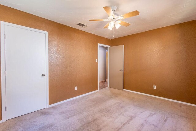 spare room with ceiling fan and light carpet