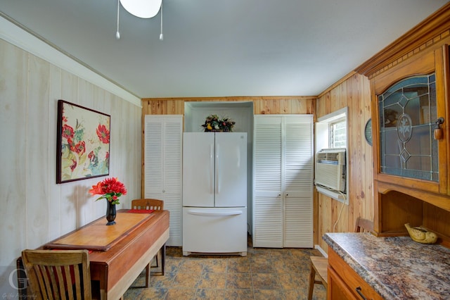 kitchen featuring dark countertops, wooden walls, brown cabinets, and freestanding refrigerator