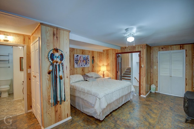 bedroom featuring connected bathroom and wood walls