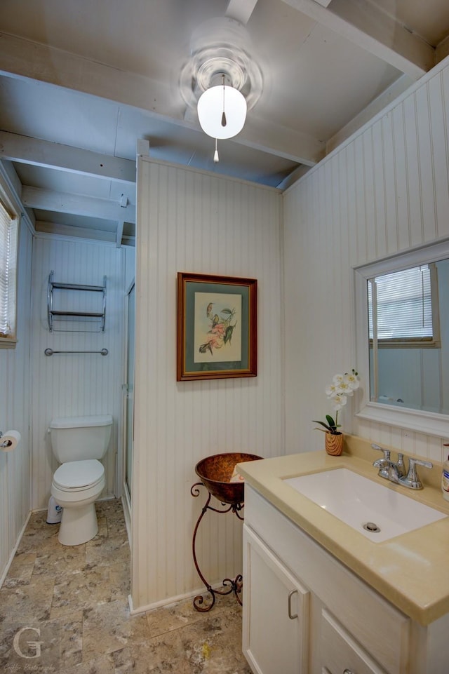 full bathroom featuring a stall shower, baseboards, toilet, stone finish floor, and vanity