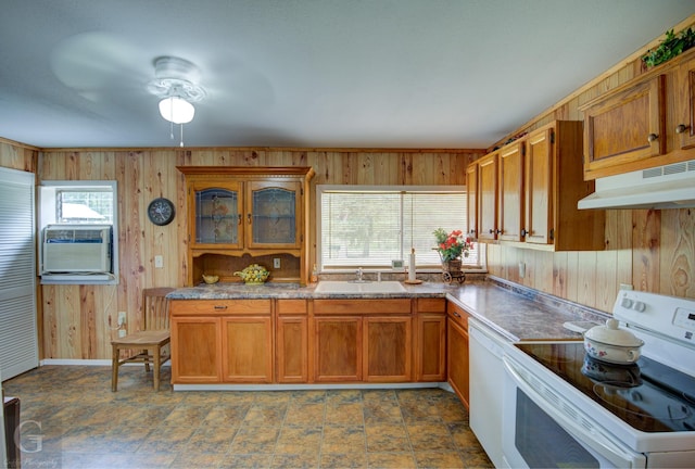 kitchen with brown cabinets, a sink, wooden walls, white appliances, and under cabinet range hood