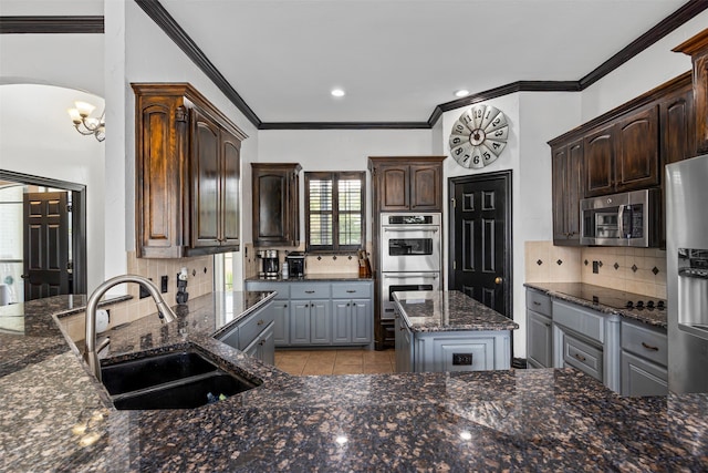 kitchen featuring a center island, appliances with stainless steel finishes, sink, dark stone counters, and decorative backsplash