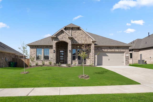 view of front of home featuring a front yard, a garage, and central air condition unit