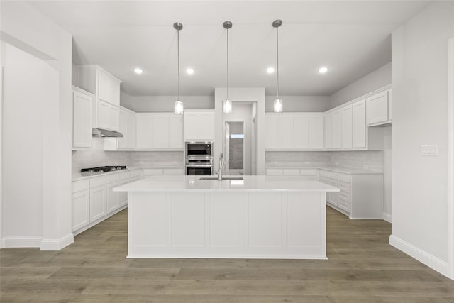 kitchen featuring a kitchen island with sink, light wood-type flooring, and white cabinetry