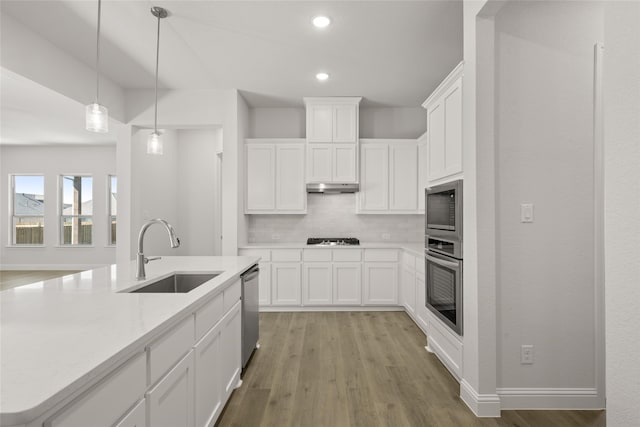 kitchen with sink, backsplash, white cabinetry, stainless steel appliances, and light hardwood / wood-style flooring