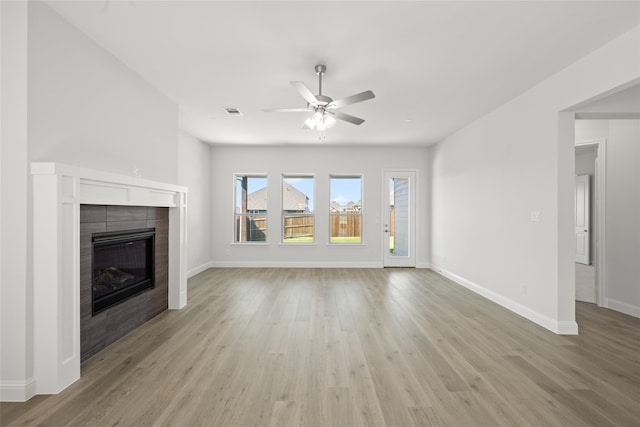 unfurnished living room featuring light hardwood / wood-style floors, a tile fireplace, and ceiling fan