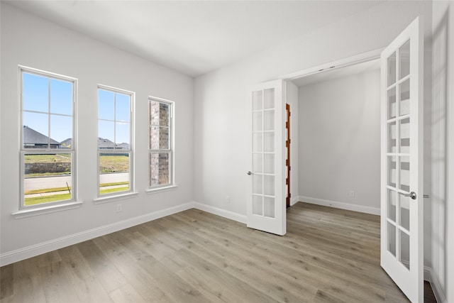 spare room featuring french doors and light hardwood / wood-style floors