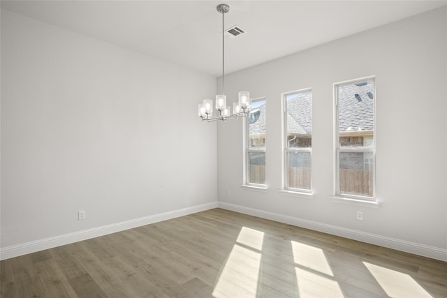 empty room featuring light hardwood / wood-style flooring and a notable chandelier