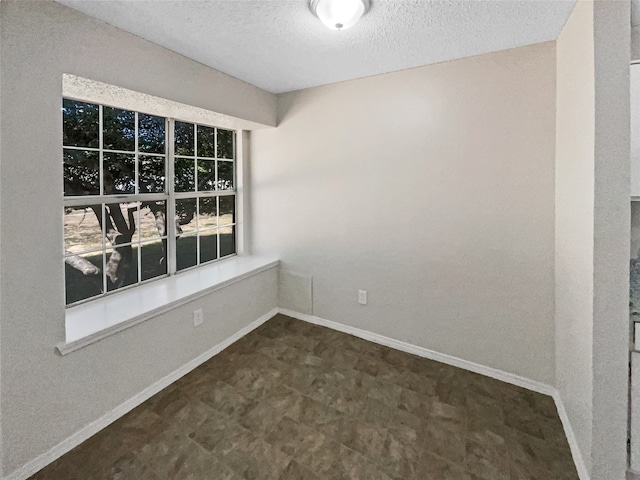 unfurnished room with a textured ceiling and dark tile patterned floors