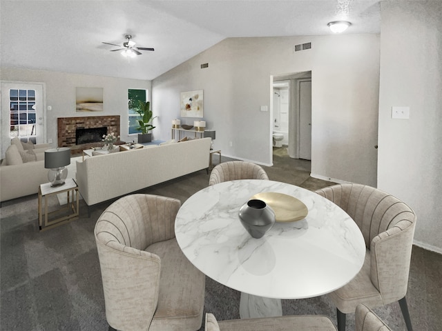 dining area with carpet, vaulted ceiling, ceiling fan, and a fireplace