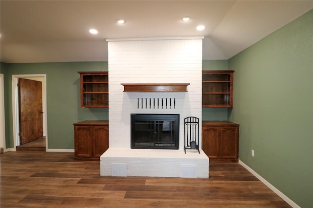 unfurnished living room featuring dark wood-style flooring, visible vents, a fireplace, and baseboards