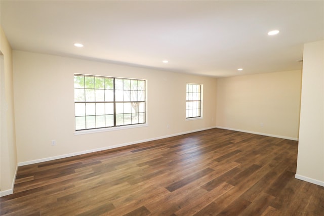 spare room featuring baseboards, dark wood-type flooring, and recessed lighting