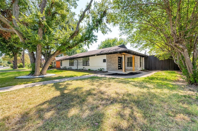 rear view of property featuring brick siding, a lawn, and fence