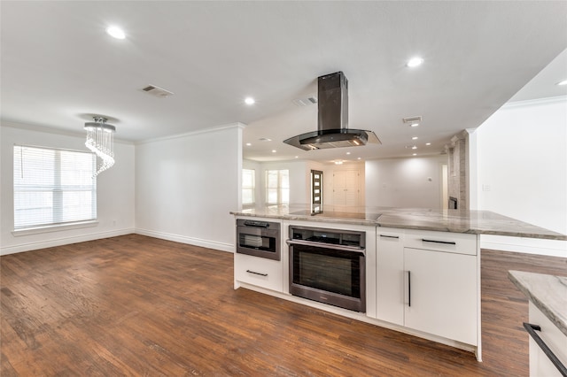 kitchen featuring oven, dark hardwood / wood-style flooring, ornamental molding, island range hood, and white cabinets