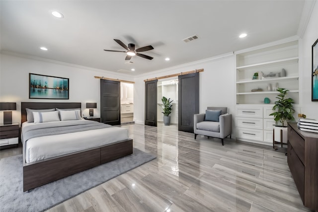 bedroom featuring ornamental molding, light wood-type flooring, connected bathroom, ceiling fan, and a barn door