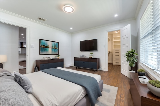 bedroom with a spacious closet, dark wood-type flooring, ornamental molding, and a closet