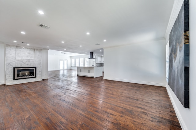 unfurnished living room featuring ornamental molding, dark hardwood / wood-style flooring, and a fireplace