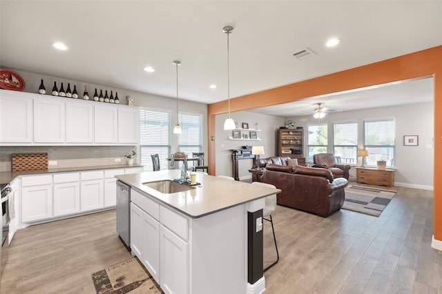 kitchen with white cabinets, appliances with stainless steel finishes, sink, hanging light fixtures, and a center island with sink