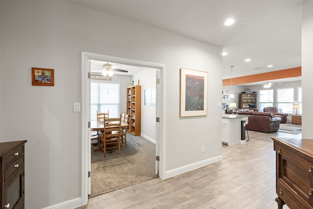 hall with a wealth of natural light and light hardwood / wood-style flooring