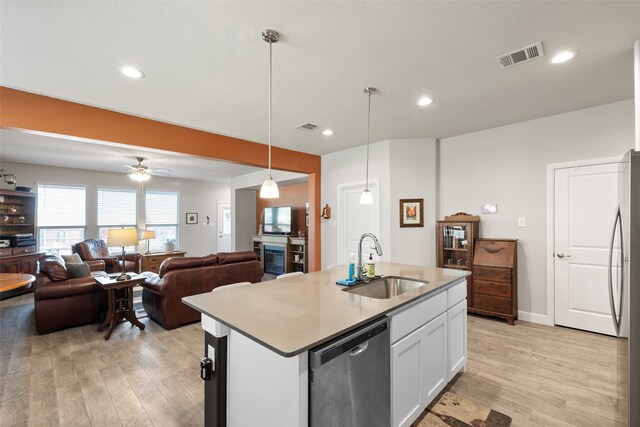 kitchen featuring appliances with stainless steel finishes, a kitchen island with sink, decorative light fixtures, white cabinets, and sink