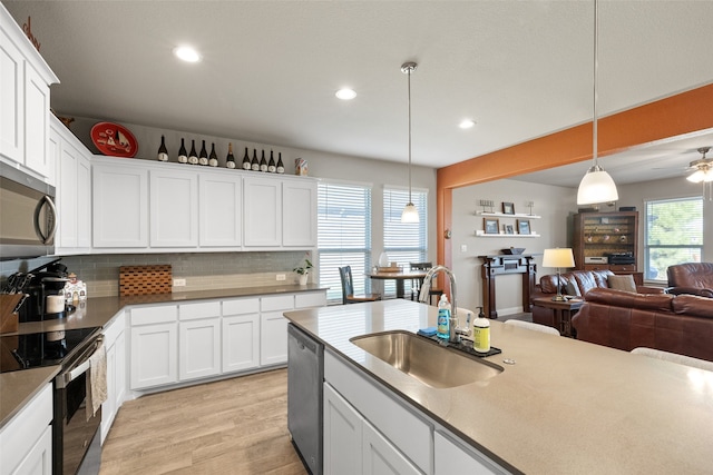 kitchen with a wealth of natural light, decorative light fixtures, stainless steel appliances, decorative backsplash, and sink