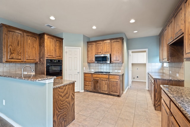 kitchen with dark stone counters, tasteful backsplash, light tile patterned floors, sink, and stainless steel appliances