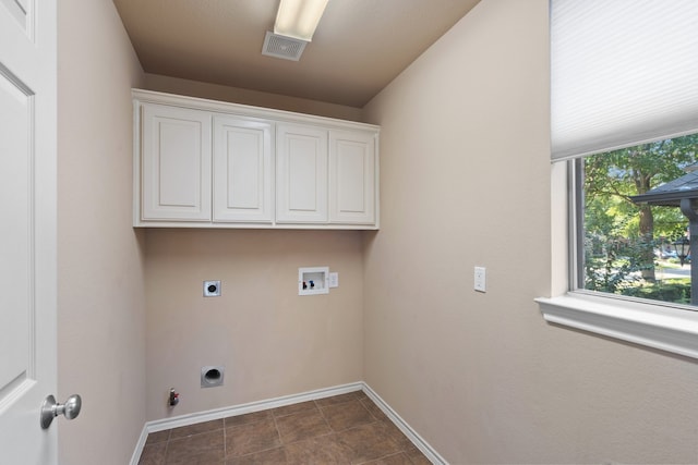 washroom featuring electric dryer hookup, hookup for a washing machine, cabinets, and dark tile patterned floors