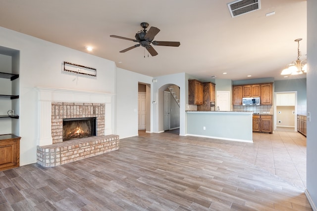 unfurnished living room with ceiling fan, light hardwood / wood-style floors, and a brick fireplace