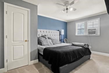 carpeted bedroom featuring ceiling fan and ornamental molding