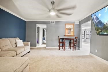 carpeted living room with ceiling fan and crown molding