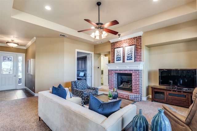 living room with a fireplace, tile patterned flooring, a tray ceiling, and ceiling fan