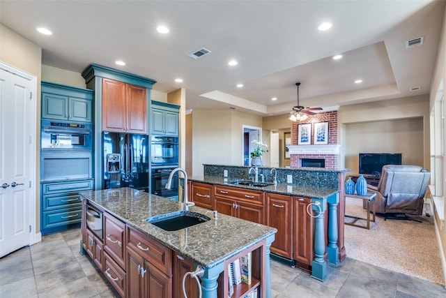 kitchen with a center island with sink, black appliances, and sink