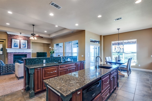 kitchen with a kitchen island with sink, a fireplace, and decorative light fixtures