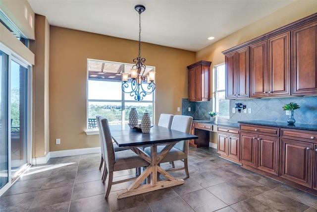 dining area featuring dark tile patterned floors and a notable chandelier