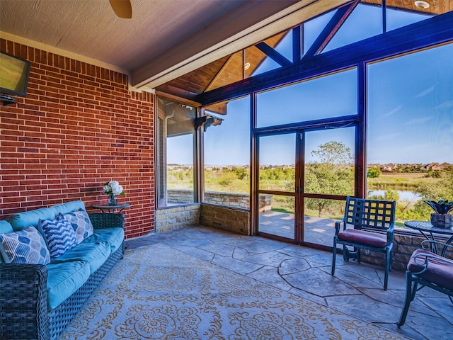 sunroom with a water view, vaulted ceiling, and ceiling fan